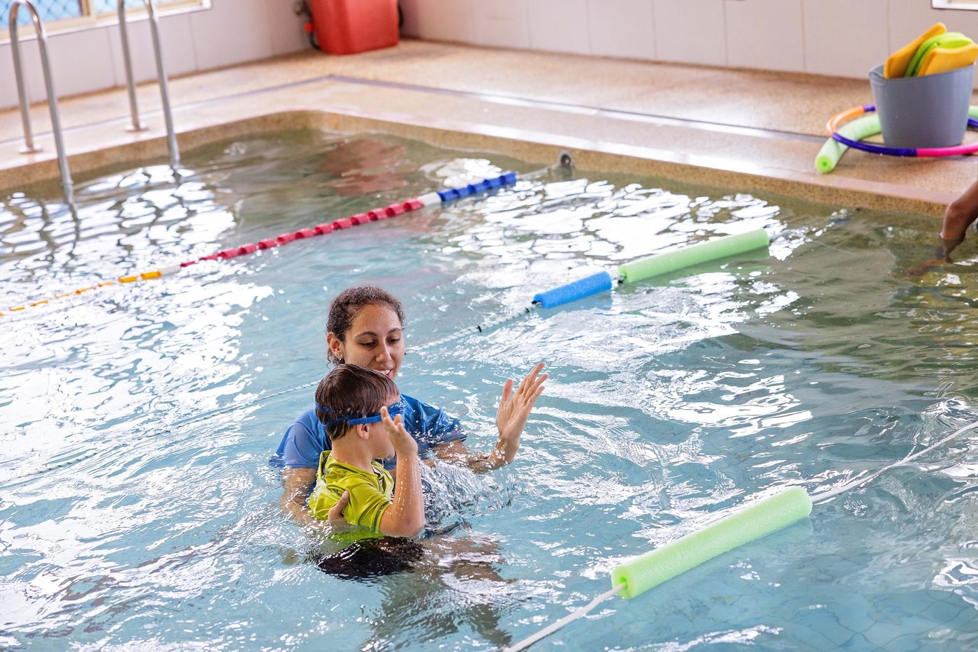 Instructor supporting a young swimmer